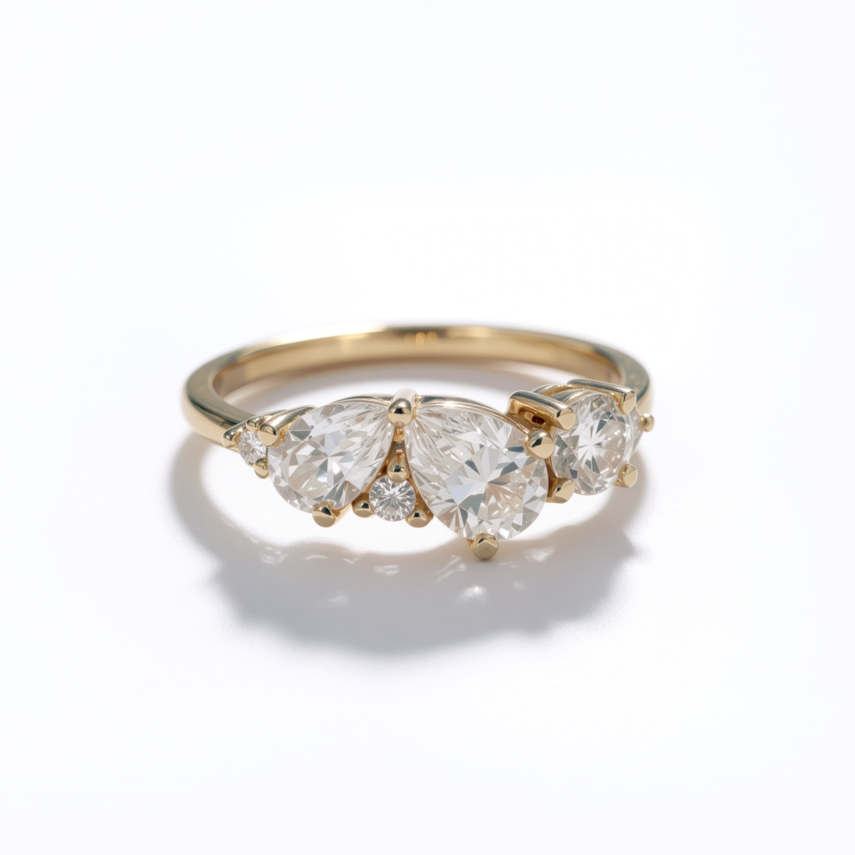 Gold ring with three pear-shaped diamonds on a white background