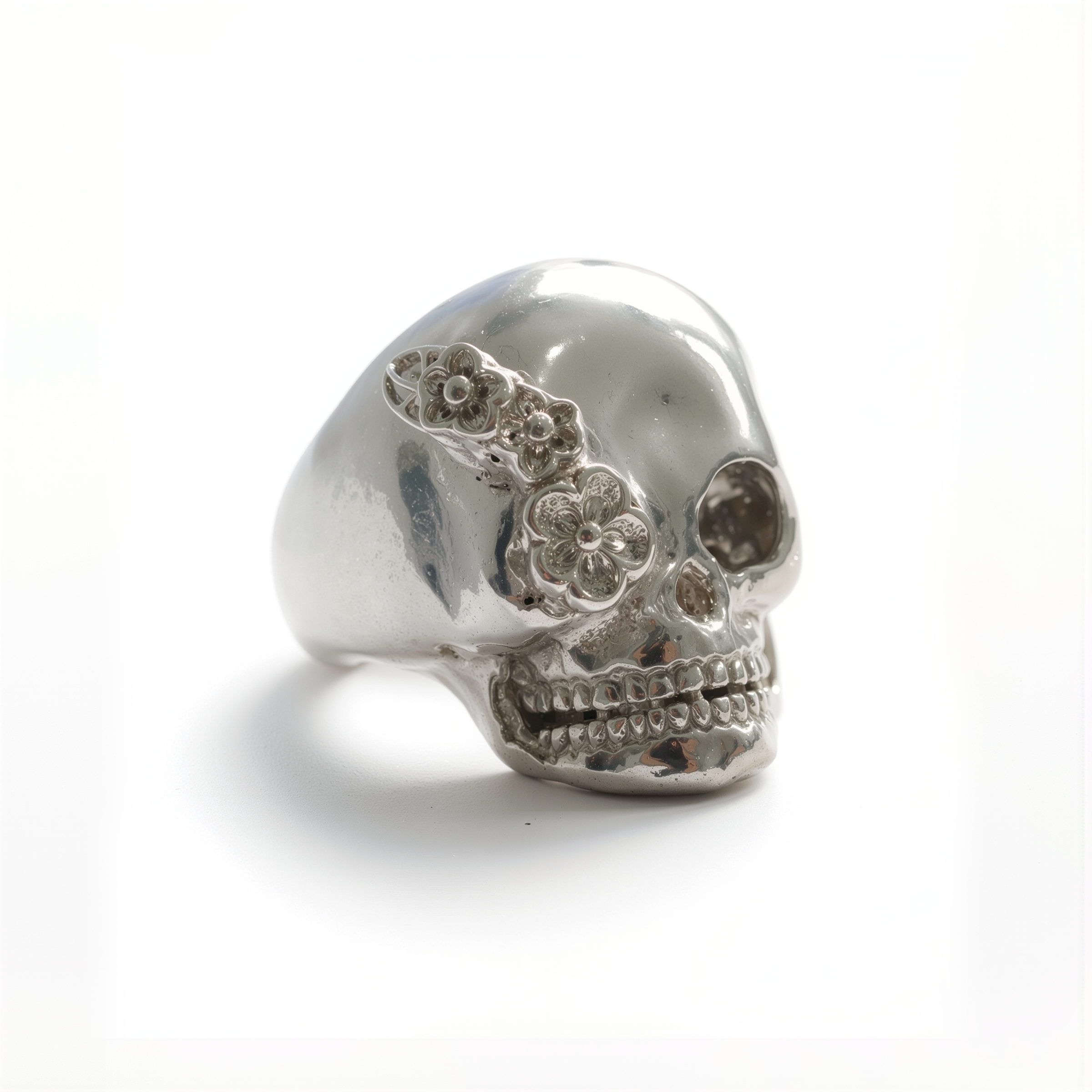Silver skull ring with floral details on a white background