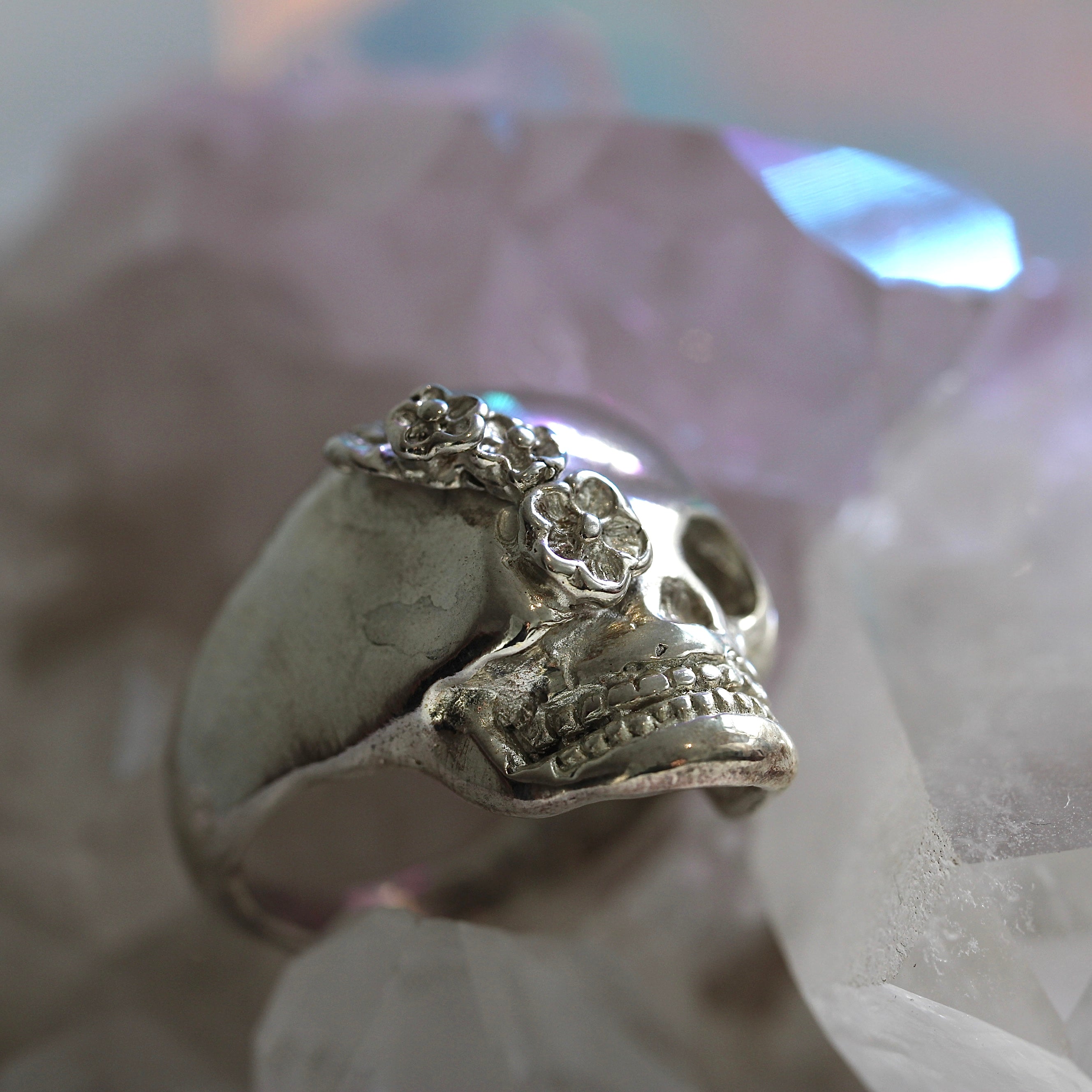 Silver skull ring with floral details on a white background