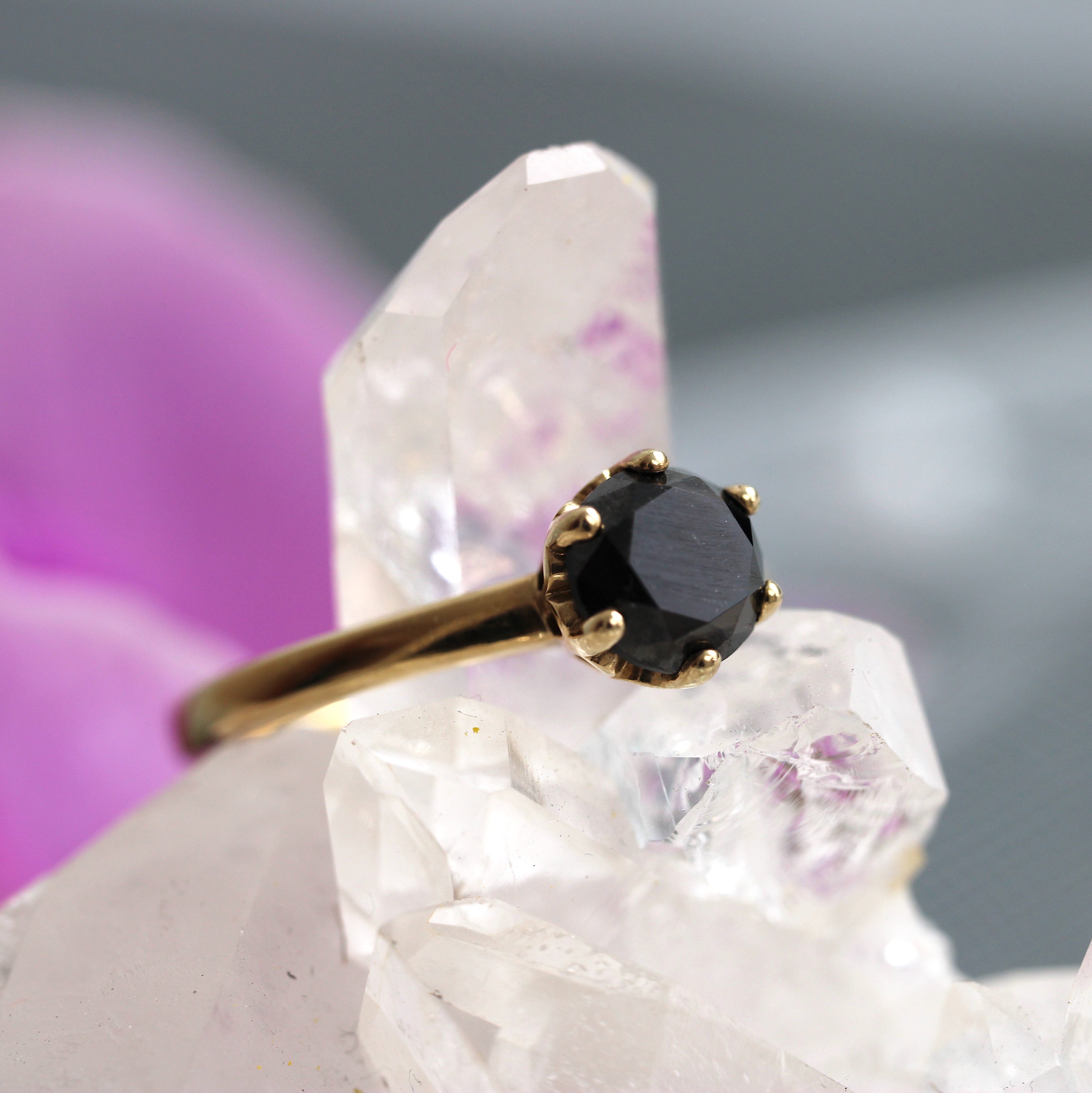 Gold ring with a black gemstone on a crystal background