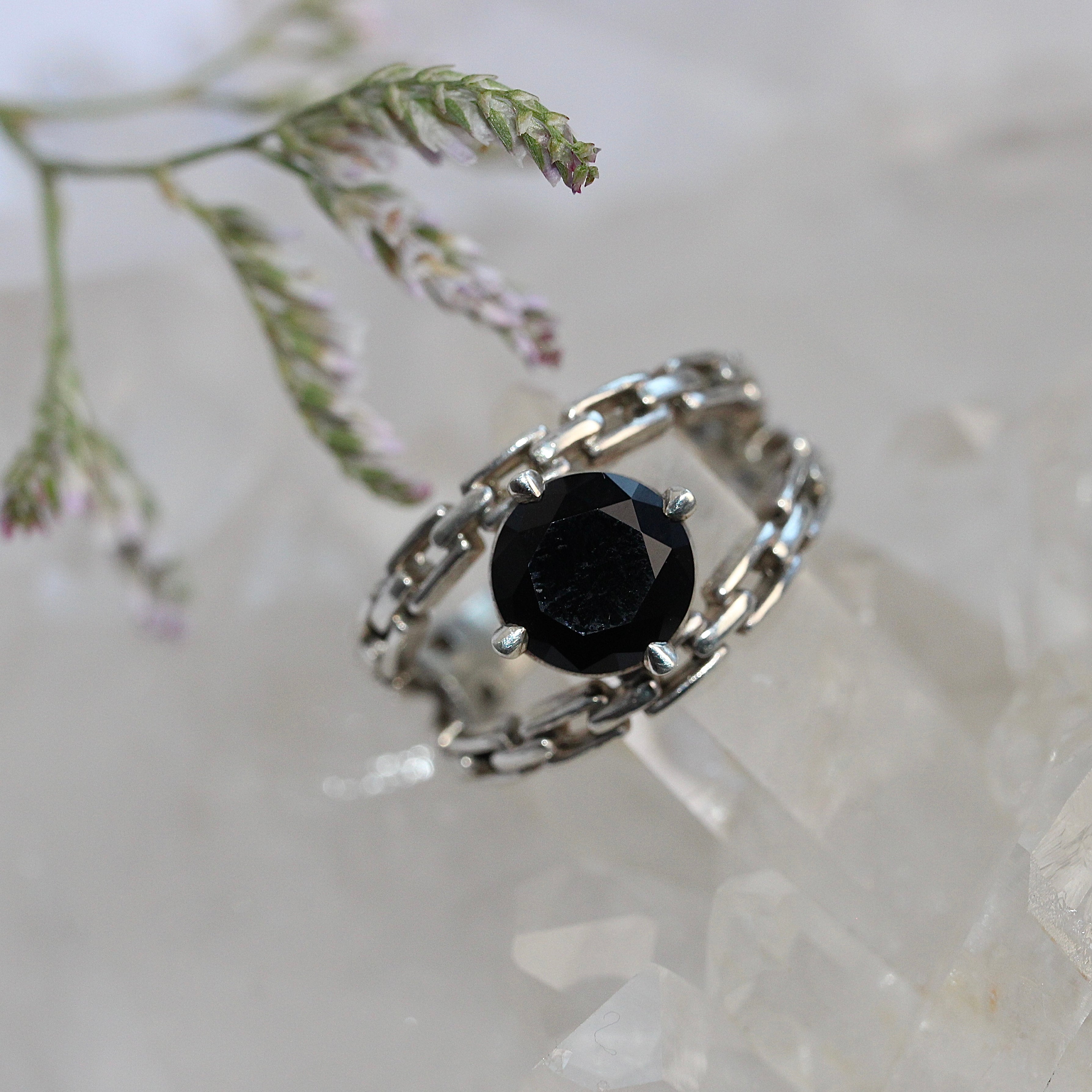 Silver ring with a black gemstone on a light background