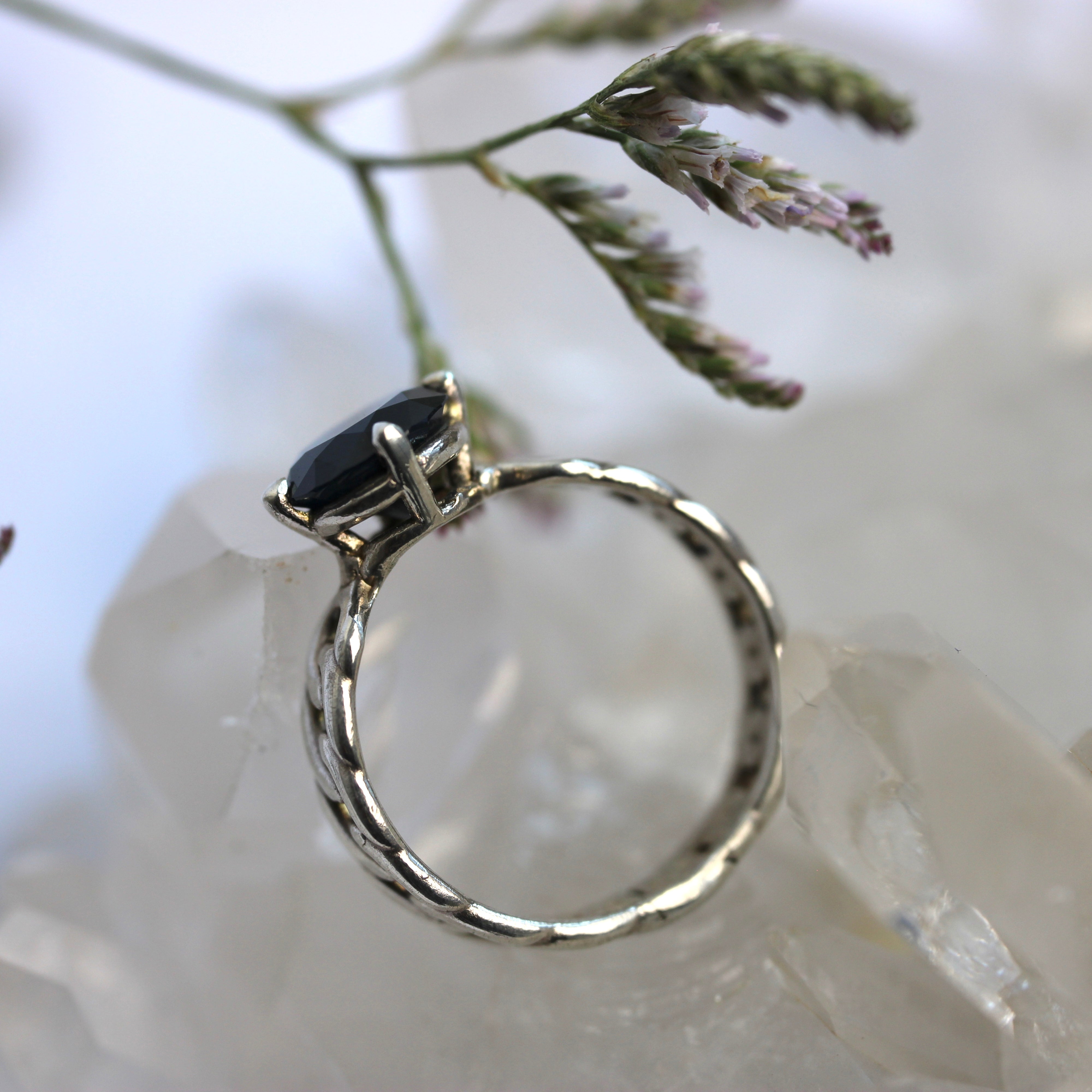 Silver ring with a black gemstone on a white stone background