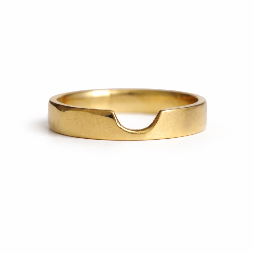 Gold wedding band with a cut out section on a white background