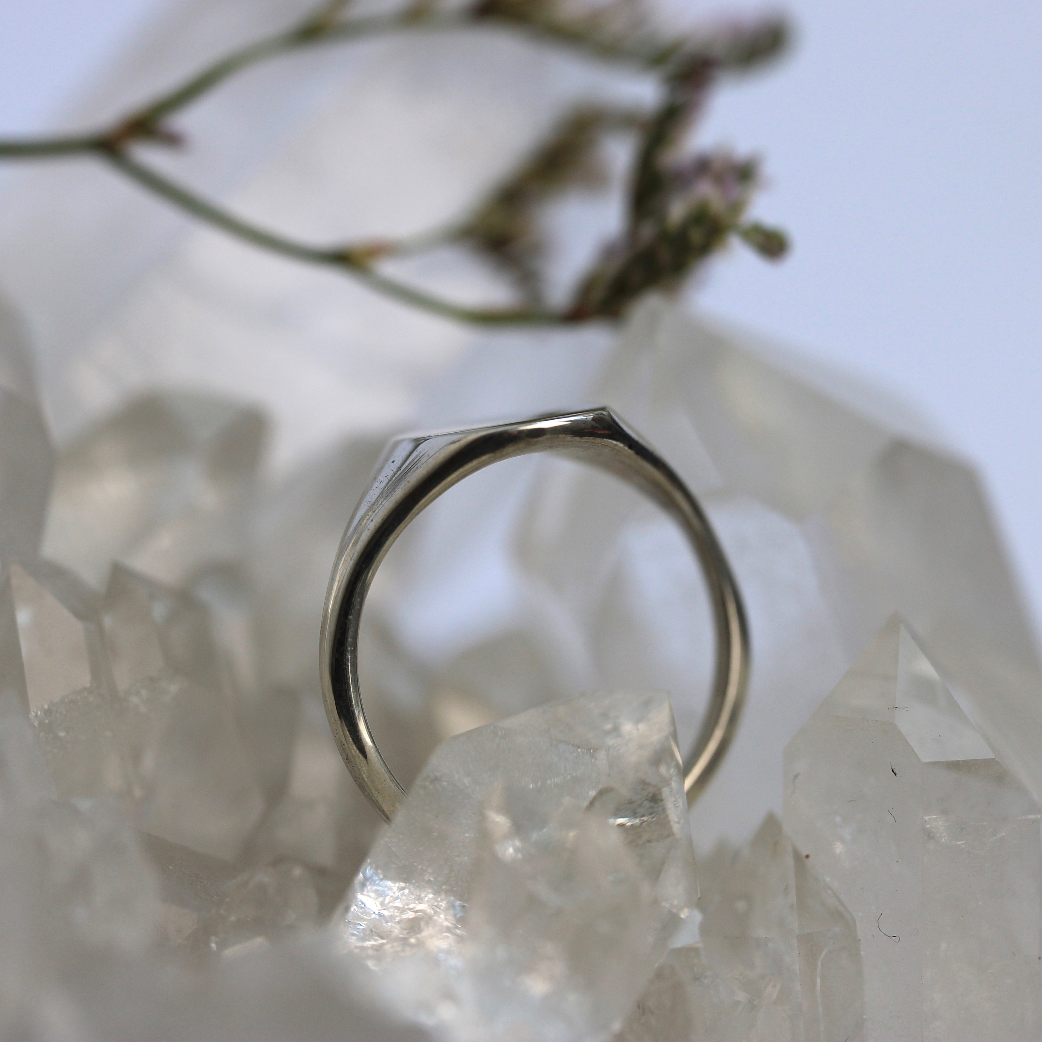 Silver ring on a crystal surface with a blurred natural background