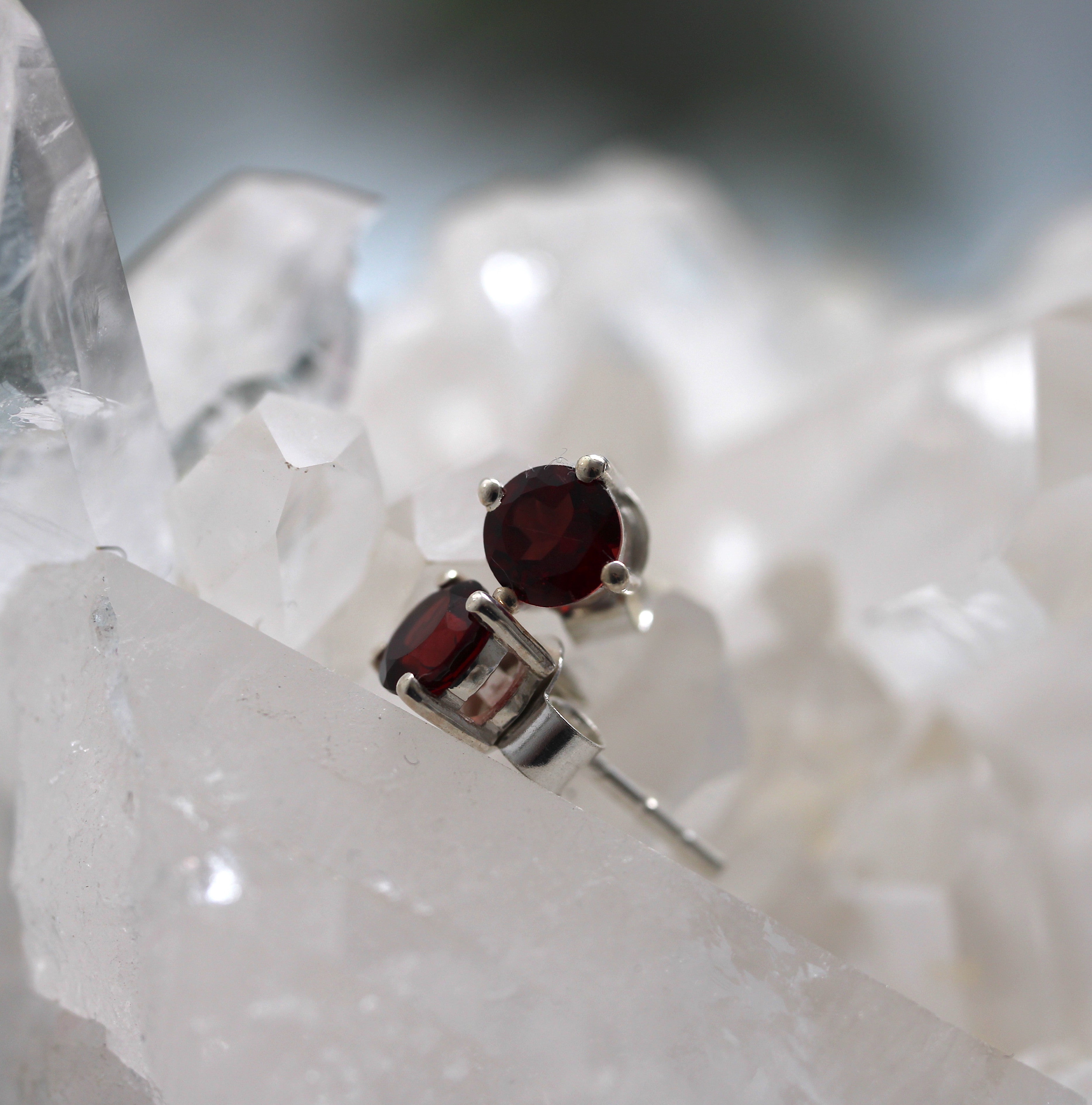 Silver earrings with red gemstones on a crystal background
