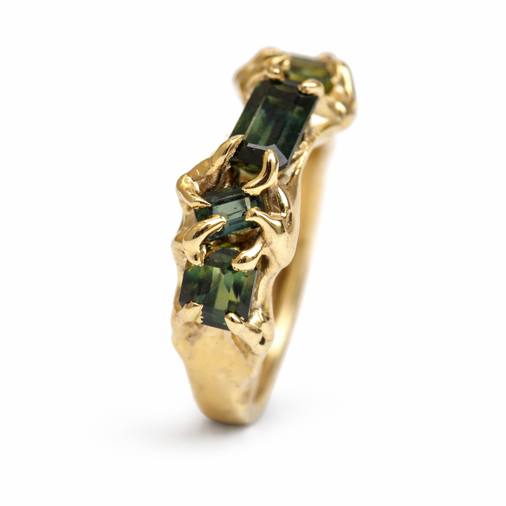 Gold ring with green sapphires on a white background