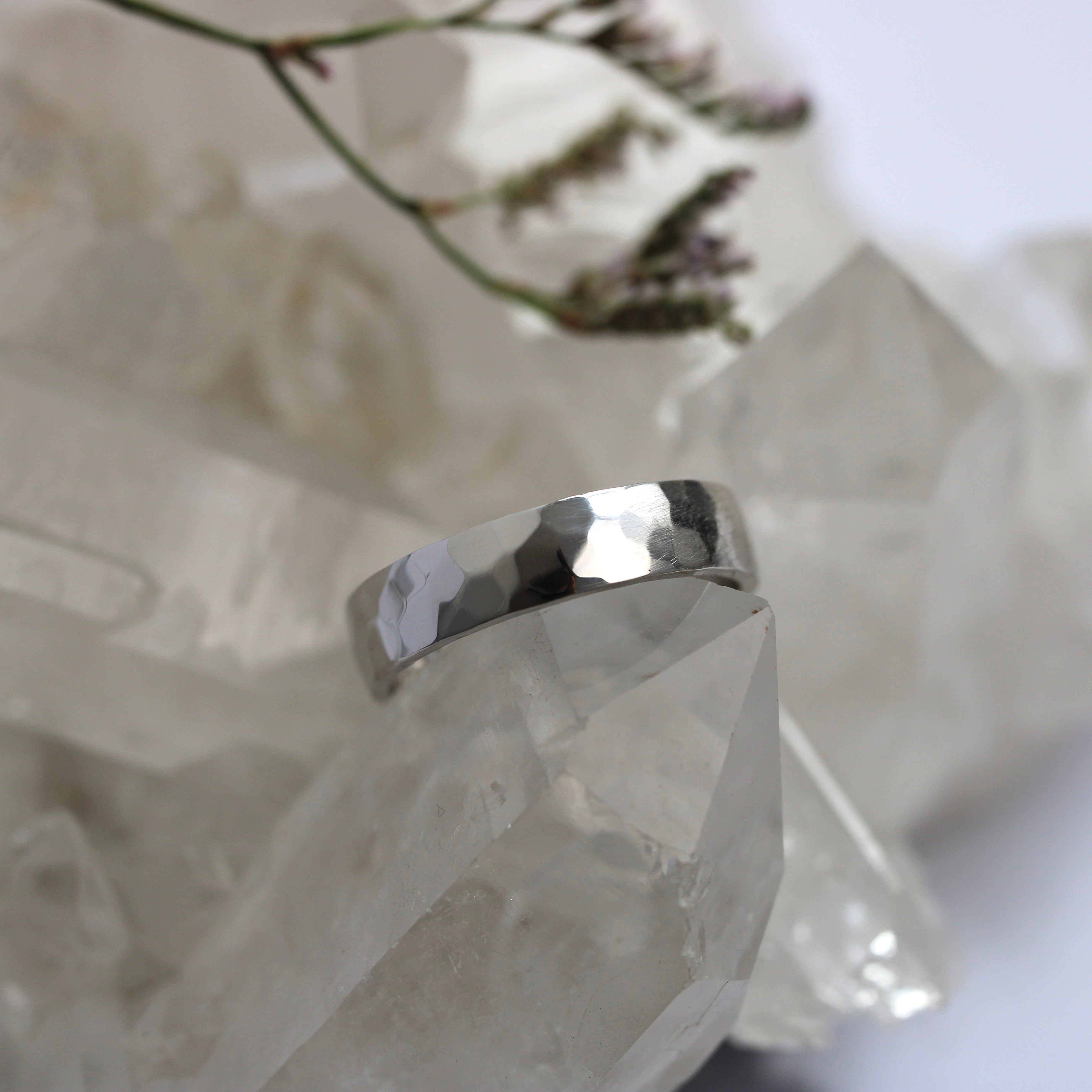 Silver ring on a crystal with blurred flowers in the background