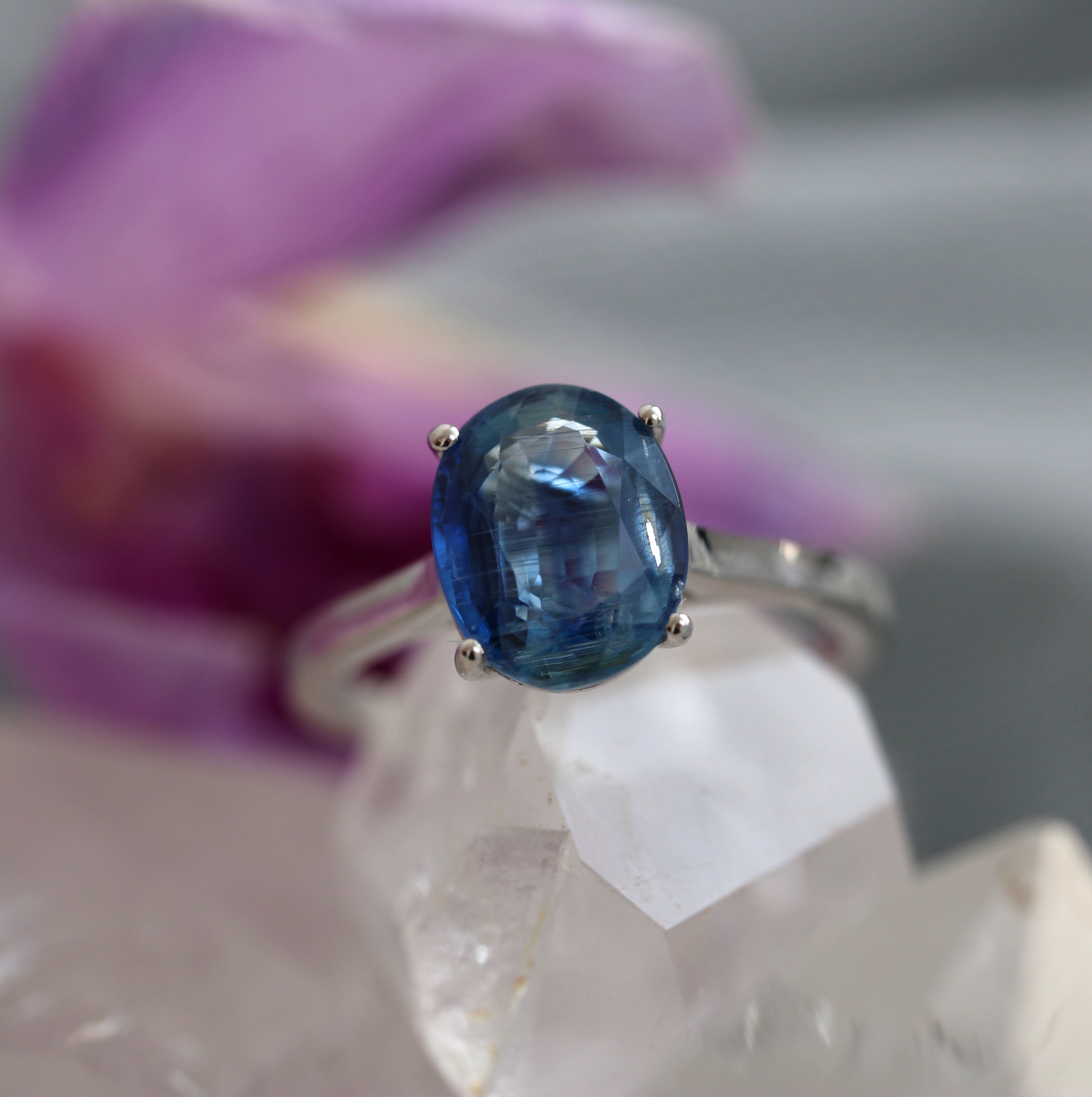 Ring with a blue gemstone held by a gloved hand against a blurred background