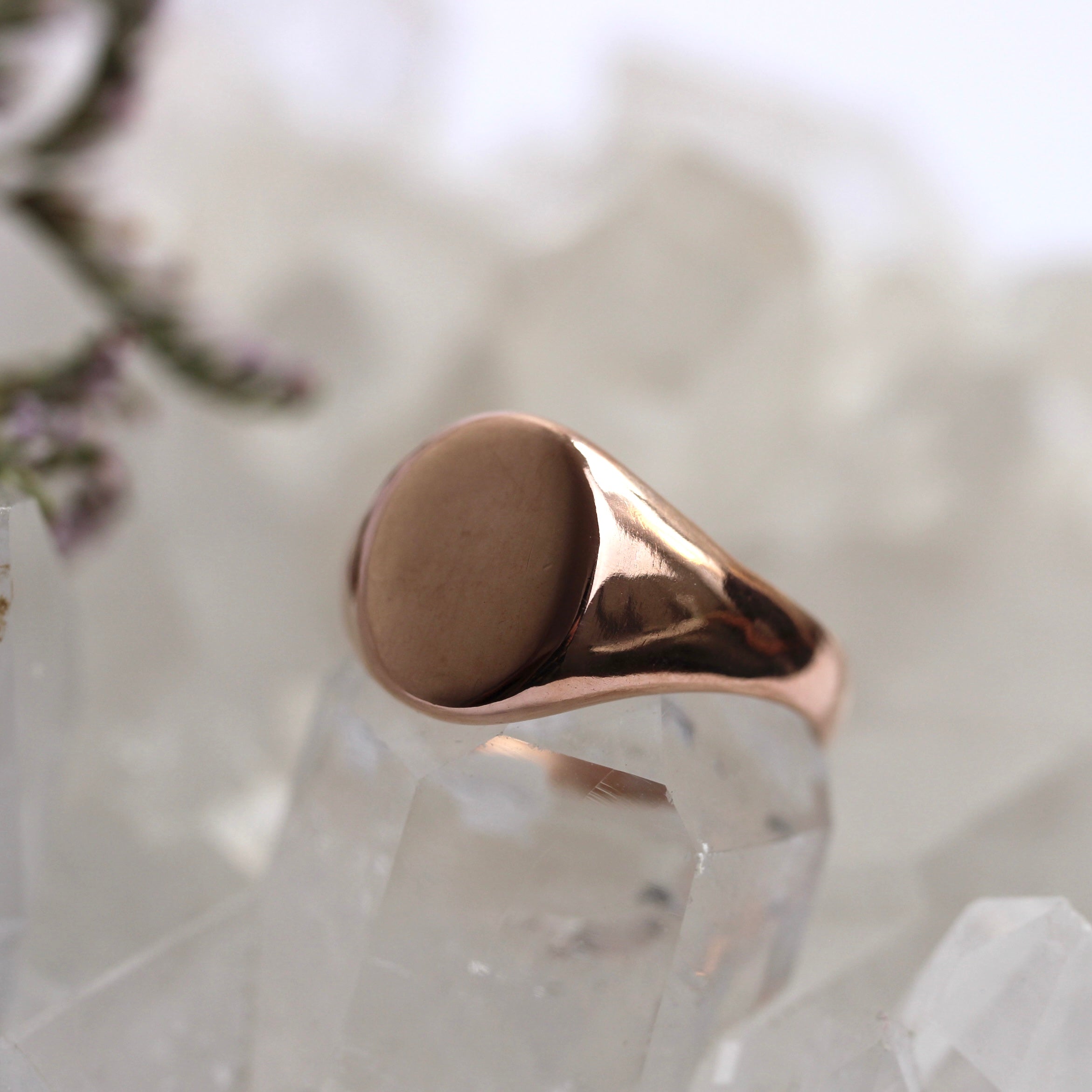 Rose gold ring on a textured white surface with blurred background