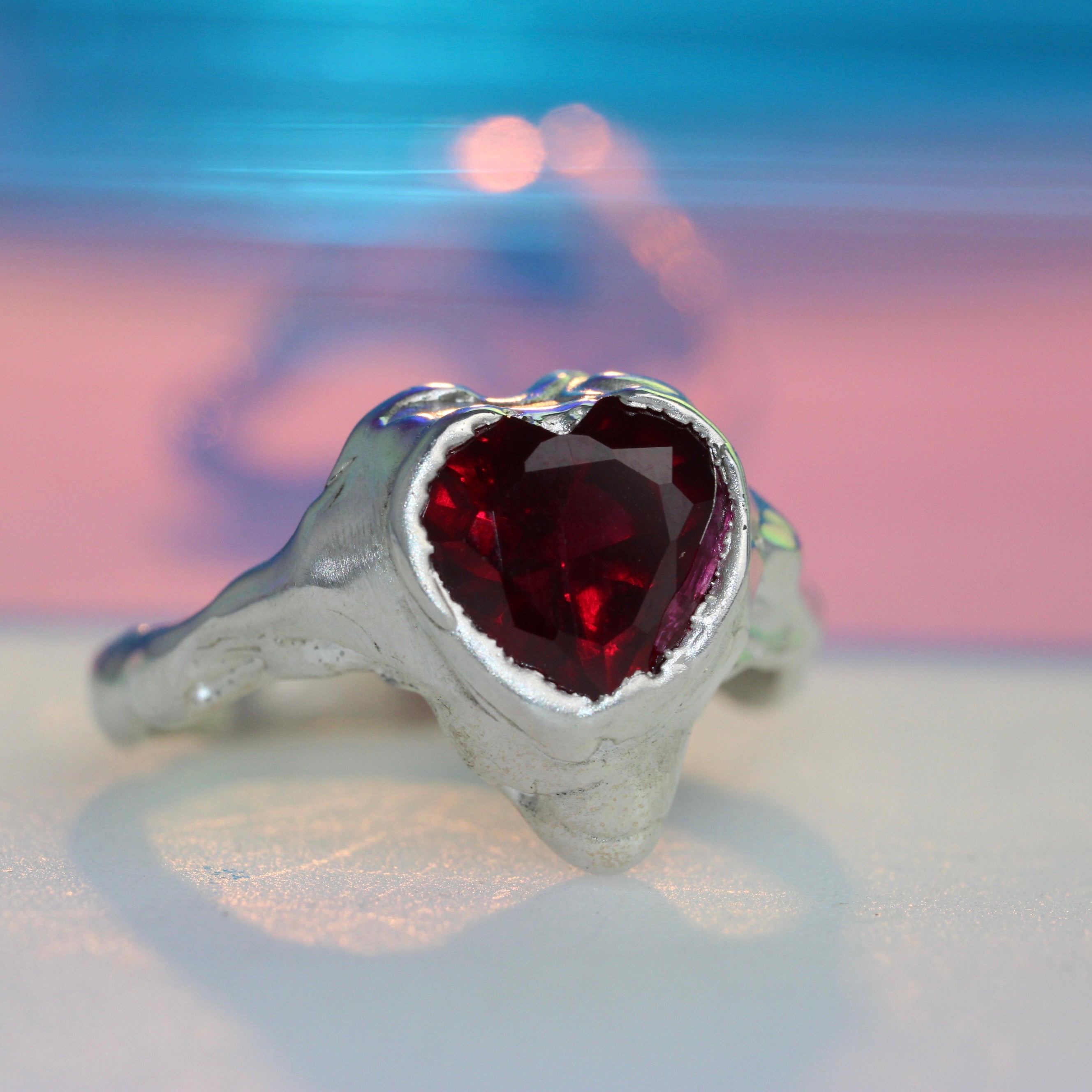 Silver ring with red gemstone on a blurred background