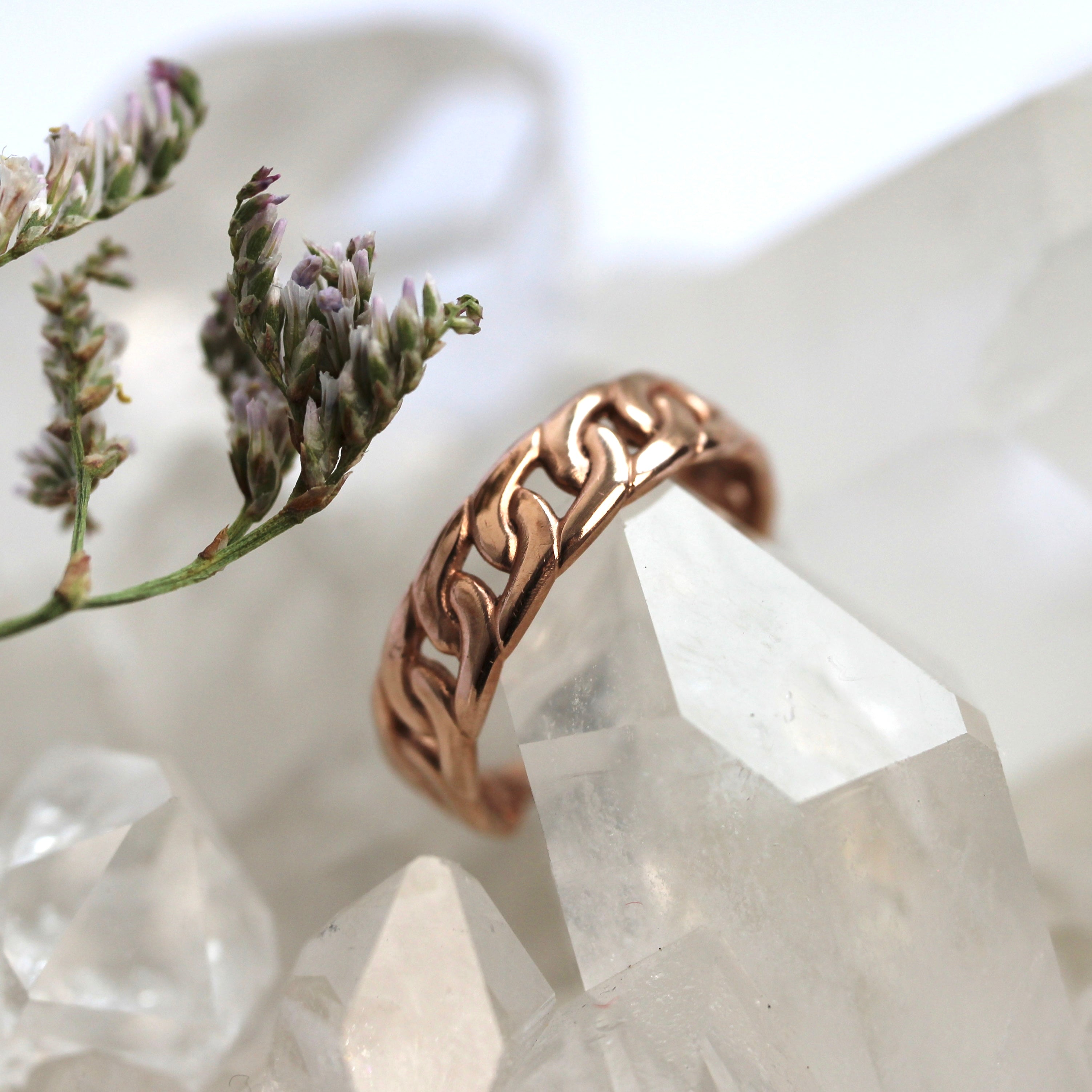 Rose gold ring on a crystal with flowers in the background