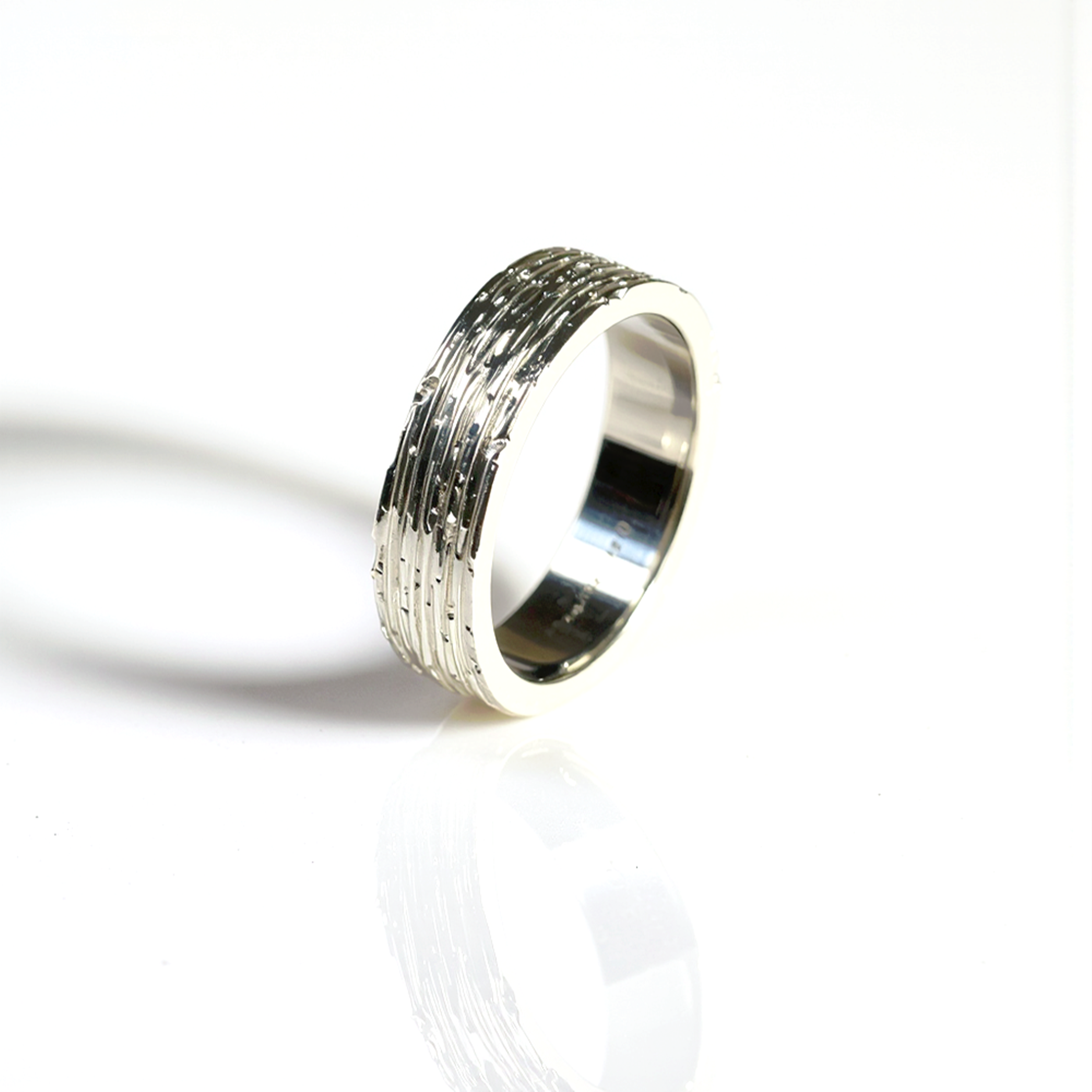 Silver ring with textured design on a white background