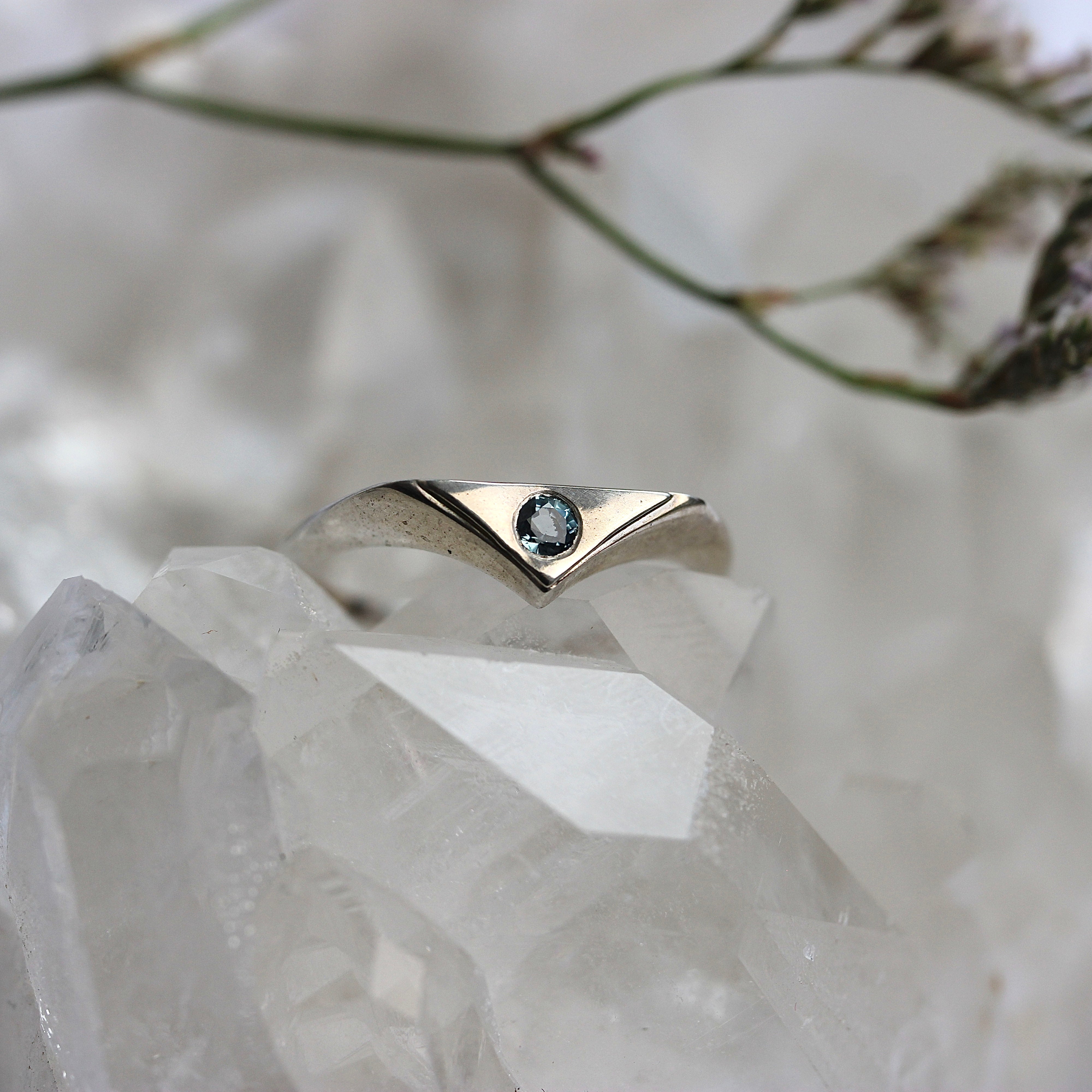 Silver ring with a gemstone on a crystal surface