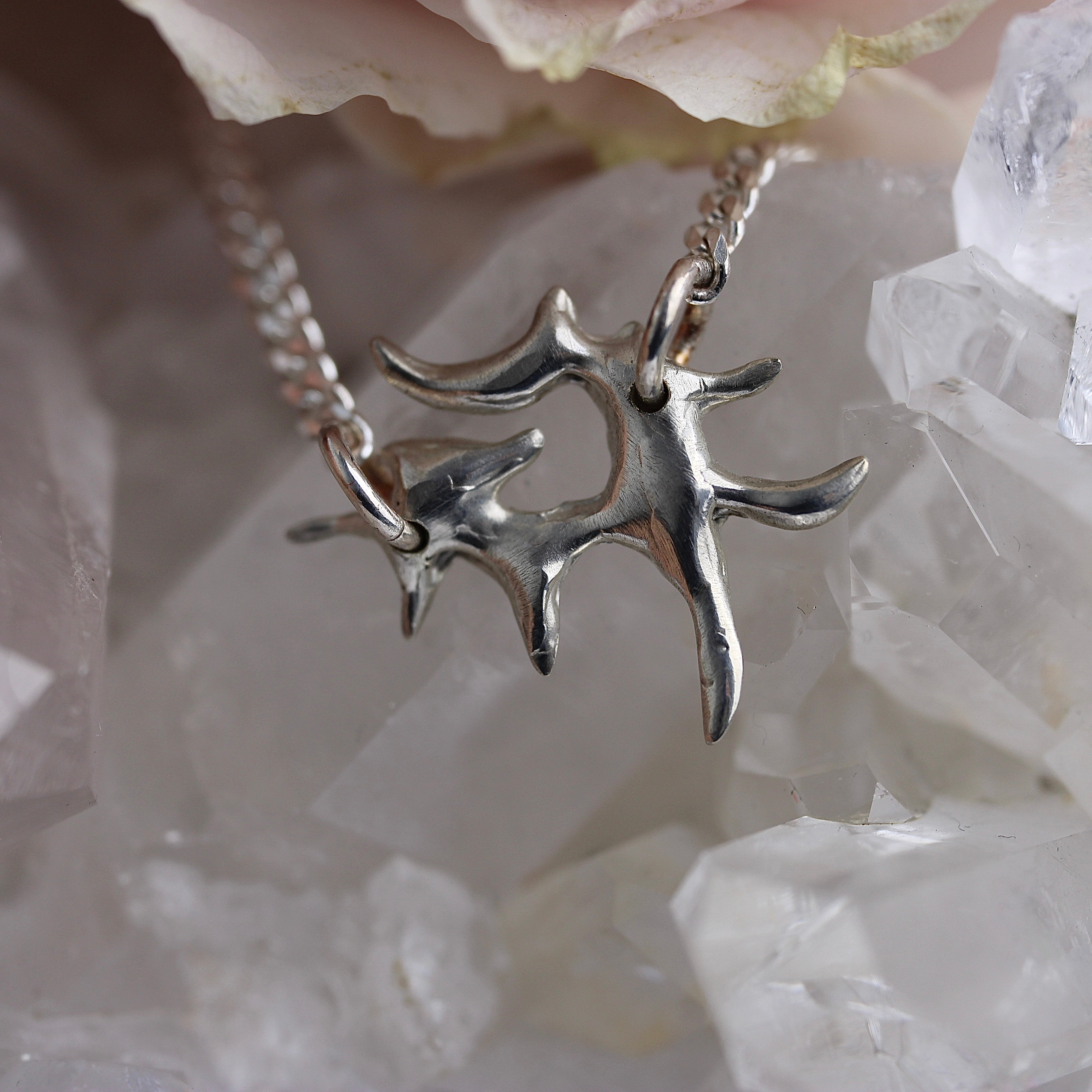 Silver star-shaped pendant on a chain against a crystal background
