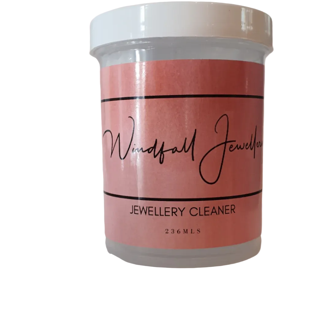 A clear plastic jar with a white lid labeled 'Woodfall Jewellery Jewellery Cleaner 230ml' on a pink background.