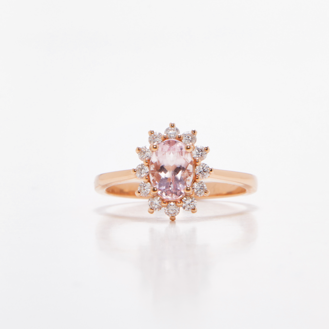 Oval floral halo diamond engagement ring in rose gold with sparkling cluster halo — classic bridal jewellery photographed on white background.