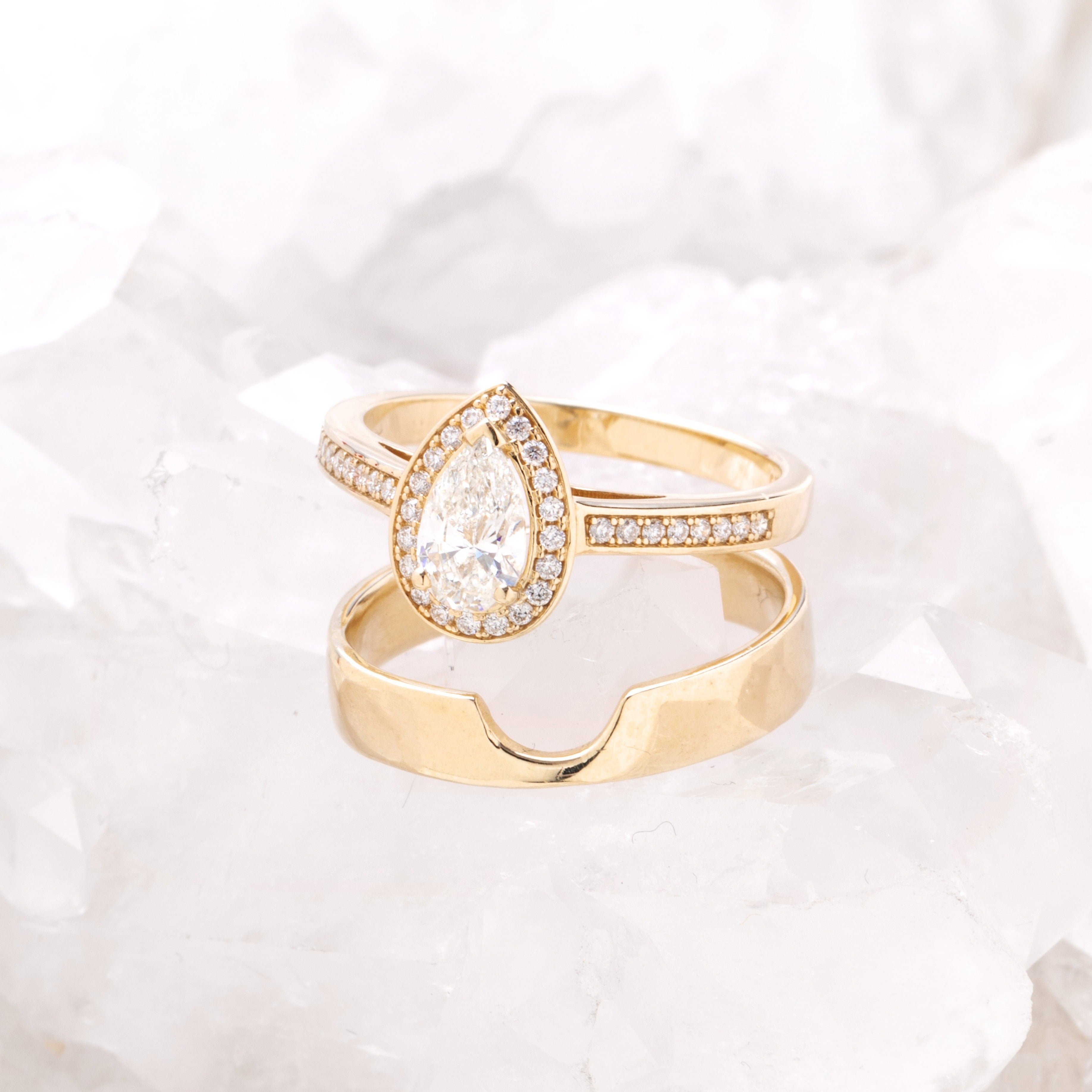 Pear halo diamond engagement ring paired with matching wedding band shown on white background — classic bridal set in yellow gold