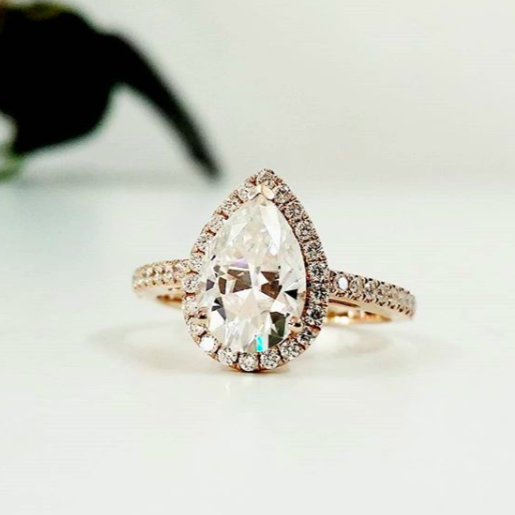 Rose gold halo diamond engagement ring with a thicker pavé band displayed on clean white background — romantic bridal jewellery photo